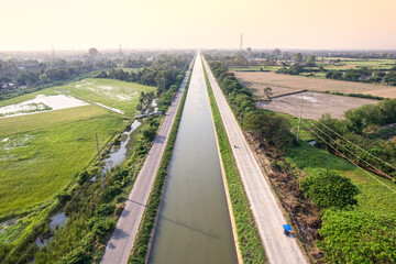 Fototapeta na wymiar Aerial view of straight irrigation canal system management among the rice field and agronomic in countryside