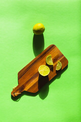 Citrus lime split on a green background on a wooden board with marked shadows