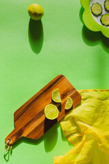 Citrus lime on a green background on a wooden board with marked shadows, yellow napkin and green plate