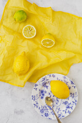 Overhead view of lemons and citrus fruits on a vibrant yellow and white background, summer sensations