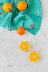 Overhead view of oranges with white background and vintage turquoise tablecloth, summer inspiration