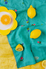 Overhead view of oranges with vintage turquoise tablecloth background and yellow napkin