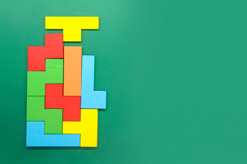 Colorful wooden Puzzle block on a green background.the concept of stacking puzzles