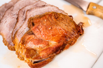 Baked pork neck, sliced to steak on kitchen board.