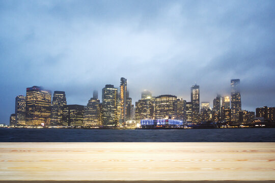 Blank wooden table top with beautiful New York skyline at evening on background, mockup