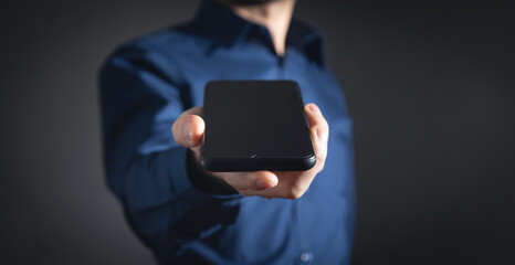Businessman holding smartphone in office.