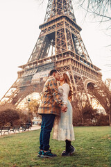A couple kissing in front of the Eiffel Tower in Paris. Romantic trip, honeymoon in Europe. France...