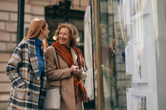 Happy Grandmother And Granddaughter Looking At Show Window At The Gallery.