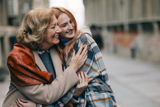 A happy grandmother and granddaughter hugs outside.