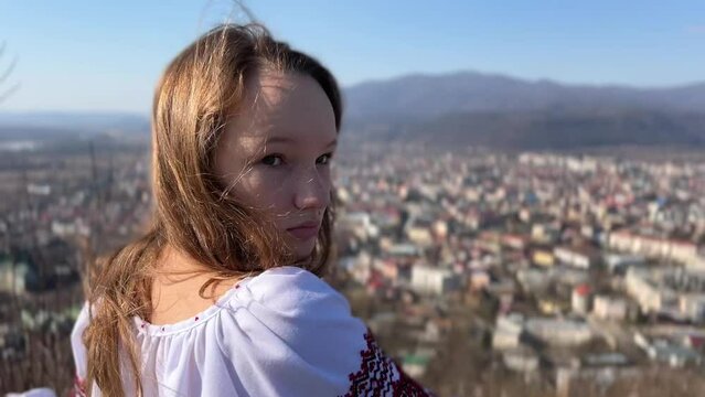 Ukrainian girl in an embroidered shirt against the background of a ruined fortress worries about the war around the mountain of devastation and hope for the best in the eyes of sadness, reproach