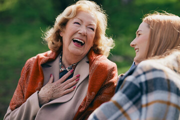 A happy senior woman laughing outside with granddaughter.