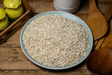 Dry oatmeal in a plate on a wooden background. Healthy and tasty food. Food for weight loss
