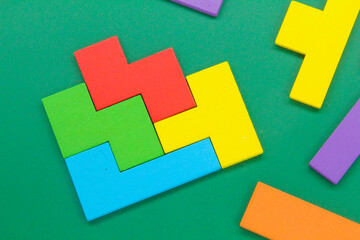 Colorful wooden Puzzle block on a green background.the concept of stacking puzzles