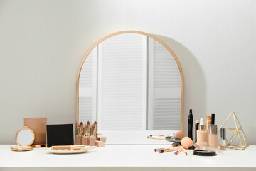 Stylish mirror on dressing table with cosmetic products