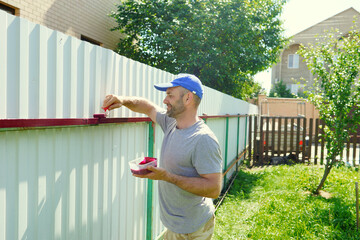 worker painting fence. Summer outdoor activity. Development. Repair. Tools 