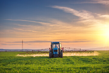 Tractor spray fertilizer spraying pesticides on green field, agriculture background concept.