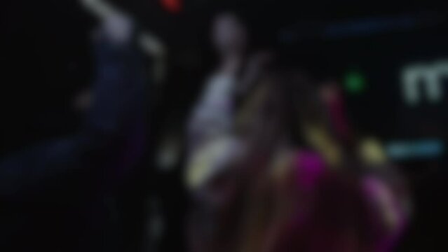 Blurry background of unrecognizable people dancing in a nightclub with flashing lights, clubbing concept