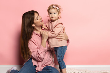 Support and care. Young woman and little girl, mother and daughter isolated on pink studio background. Mother's Day celebration. Concept of family, childhood, motherhood