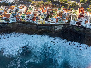 Fototapeta na wymiar Aerial view on colorful houses and black lava rocks in small village Punta Brava near Puerto de la Cruz, Tenerife, Canary islands at sunrise