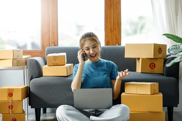 Asian woman owned business SME entrepreneur of Young Asian women working with Boxs laptop and phone for Online seller shopping at home, online marketing packaging delivery SME e-commerce concept