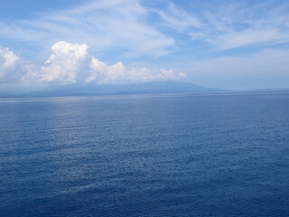 The surface of a calm sea without waves and a blue sky with clouds.