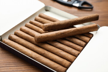 Humidor with cigars on wooden table, closeup