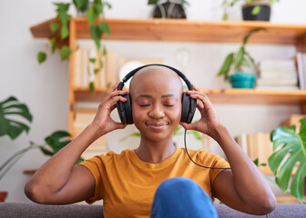 A young woman listens to music with headphones on the sofa in the living room