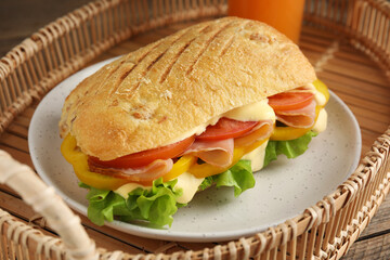 Delicious sandwich with vegetables, ham and mayonnaise served on wicker tray, closeup