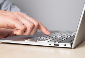 Obraz na płótnie Canvas Man hand closeup pressing enter key. Man sitting at table and working on laptop. High quality photo