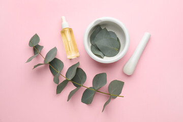 Flat lay composition with bottle of eucalyptus essential oil and plant branches on pink background