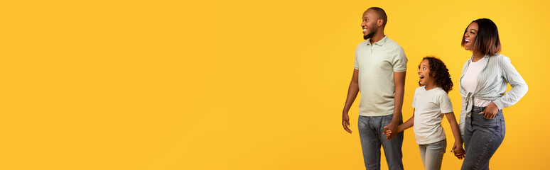 Obraz premium Excited black family looking at copy space on yellow, banner