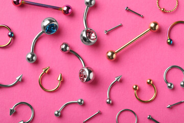 Stylish piercing jewelry on pink background, flat lay