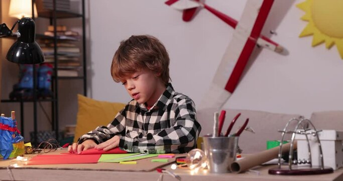 young boy folding a paper airplane and ships, causasian boy playing with paper airplanes, future engineer designer, hobby