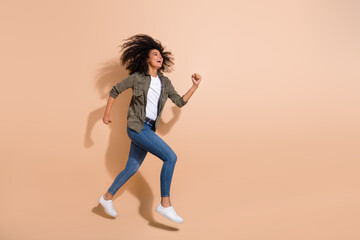 Fototapeta na wymiar Full length body size view of pretty cheerful girl jumping running enjoying isolated over beige pastel color background