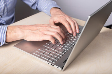 Man hands closeup typing on laptop keyboard. Data search, distant work and education, online shopping and booking concept. Man sitting at desk with computer. High quality photo