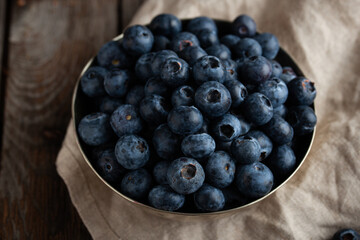 Bowl of fresh blueberries on rustic wooden table with copy space.