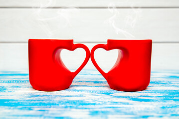 two heart shaped mugs with tea on blue background
