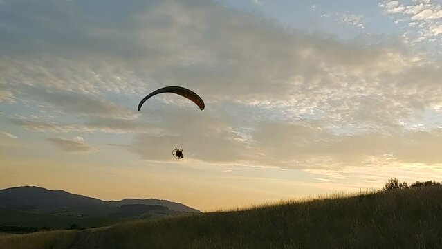 Paraglider flying on the parachute during sunset on the meadow. Slovakia