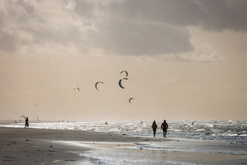 People walking along North Sea beach in Kijkduin with kitesurfer in the background