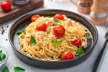 Spaghetti with baked feta and cherry tomatoes on a gray background.