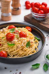 Pasta with baked feta with cherry tomatoes and herbs on a gray background.