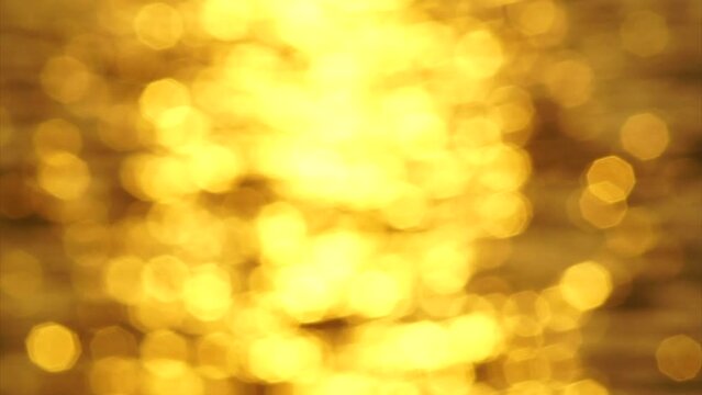 Golden bokeh light blurred background reflected on sea surf