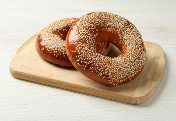 Delicious fresh bagels with sesame seeds on white wooden table