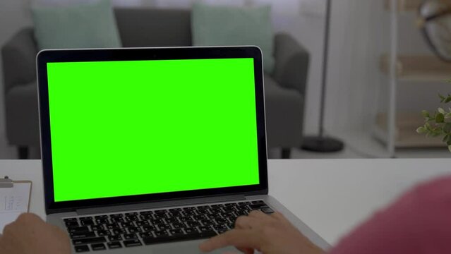 Woman working at home on with laptop green screen. woman using laptop computer indoor living room, blank green screen mockup copy space.