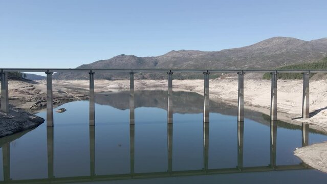 Drone passing under bridge on old dam of Aceredo during dry season, Spain. Aerial forward