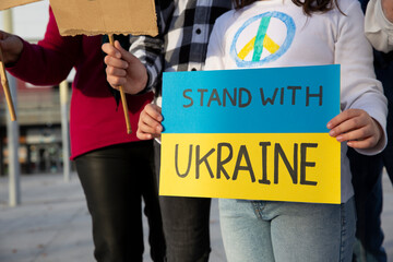 Anti-war demonstrators protest in the street against the invasion of Russian military troops in Ukraine. Group of unrecognizable people.