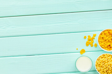 Corn cereals in bowls with milk on mint green wooden background top view space for text