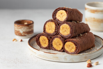 Banana stuffed chocolate crepes on gray background. Clean eating concept, vegan food. copy space