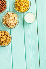 cereals, oatflakes and cornflakes with milk for healthy breakfast on mint wooden background top view mock up