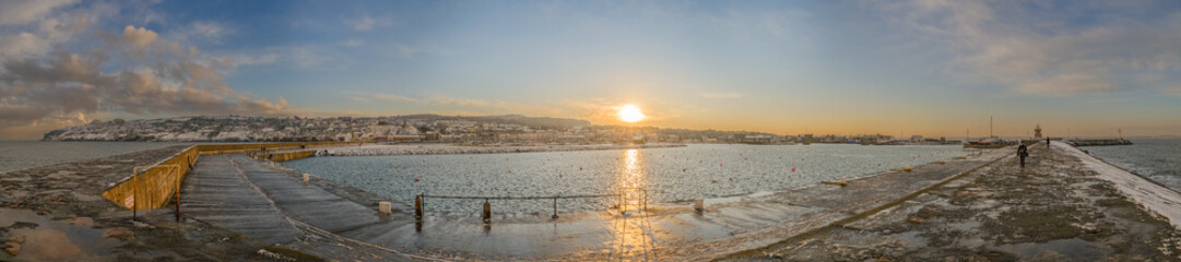 Panoramic view of Howth village and harbour with winter landscape at sunset, from the breakwater jetty, near Dublin, Ireland